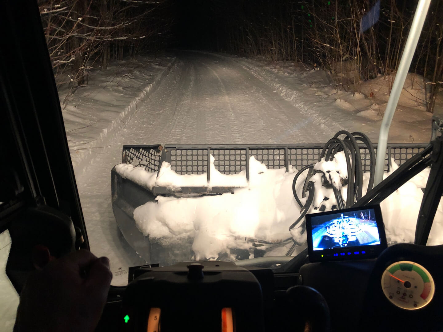 A view from the back of a vehicle as it drives down a snowy road.