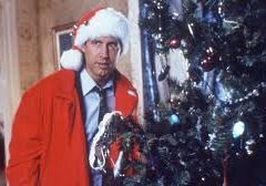A man in a santa hat and red coat standing next to a christmas tree.